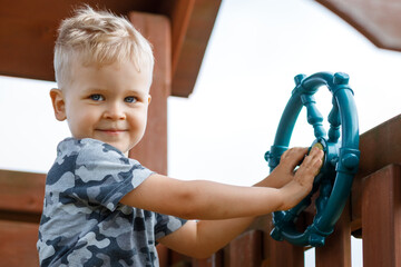 Little boy as helmsman on playground, outdoor activity - obrazy, fototapety, plakaty