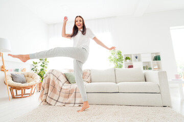 Photo of crazy carefree positive lady dance have fun barefoot enjoy weekend wear white t-shirt in room indoors