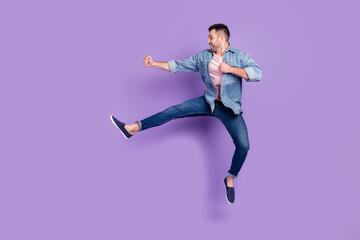 Fototapeta na wymiar Full length profile side photo of young handsome guy jump up kick karate look empty space isolated over purple color background