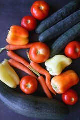 Zucchini, tomatoes, peppers, carrots and cucumbers on dark background. Flat lay.