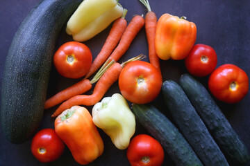 Zucchini, tomatoes, peppers, carrots and cucumbers on dark background. Flat lay.