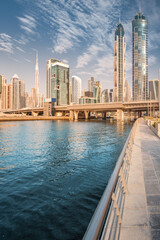 Fototapeta na wymiar Scenic vertical panorama of high skyscrapers with offices, hotels and residential buildings in UAE. Road over the bridge and flyover passes through Dubai Creek Canal