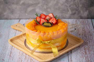 Fresh orange cake soft fudge decorated with orange pulp and strawberry for birthday cake on wooden...