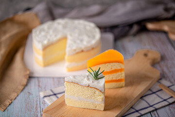 slice of homemade coconut cake and orange cake  on wooden board.