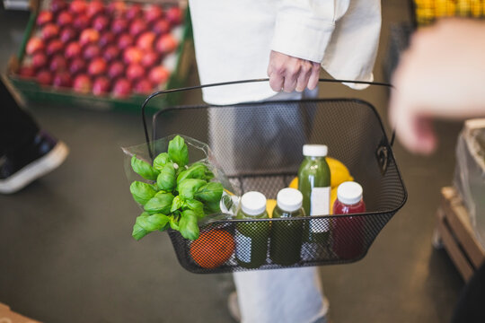 Kvinna b&auml;r korg med matvaror st&aring;ende i butik