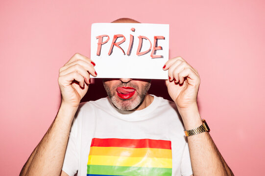 Positive gay showing paper with Pride inscription in pink studio