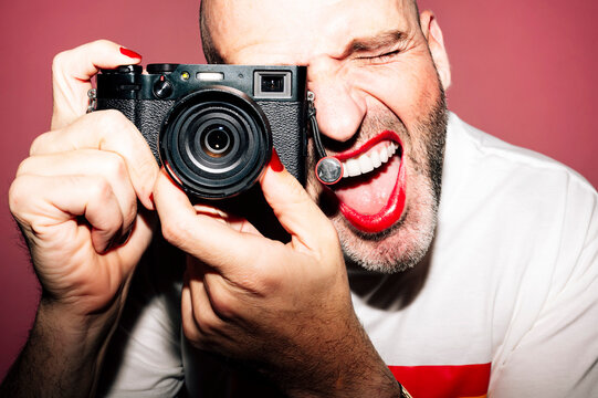 Cheerful guy with makeup taking photo on camera with opened mouth