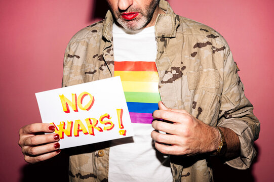 Crop homosexual male demonstrating paper with No Wars text