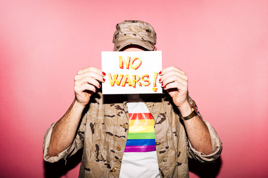 Crop anonymous homosexual male demonstrating paper with No Wars text