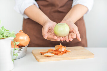 Woman holding fresh onion on her hands in kitchen. prepare to cook.