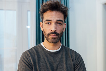 Serious young ethnic man looking at camera in contemporary room