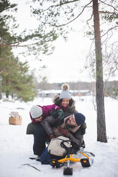 Lekfulla d&ouml;ttrar leker med pappa sittande i sn&ouml;n