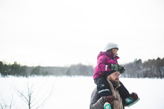 Leende man b&auml;r dotter p&aring; axlarna g&aring;ende utomhus
