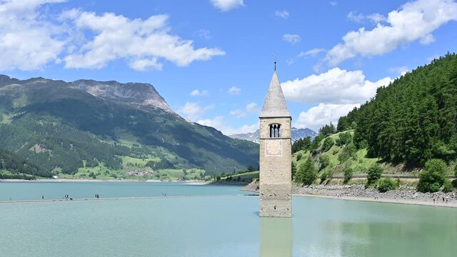 Curon, Italy, June 2021. Amazing pan footage on a beautiful summer day of the old bell tower of Curon (Graun) emerging from the waters of Lake Resia, South Tyrol, Italy.