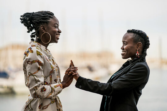 Joyful black girl friends holding and clasping hands together