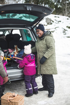 Leende mamma med dotter packar ur bil
