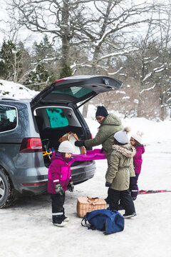 Mamma och d&ouml;ttrar packar ur bil under vinter