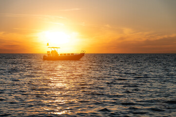 Small fishing boat catamaran at sunset. Sea transport without people in the sunset light. Twilight at sea
