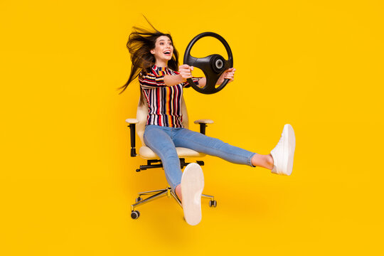 Full length body size photo girl sitting keeping steering wheel crazy imagine driving car isolated bright yellow color background