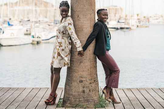 Joyful black girl friends holding and clasping hands together