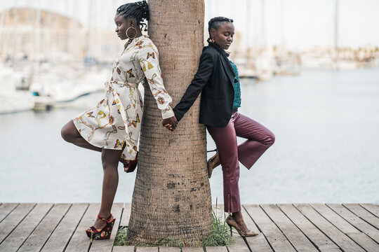 Joyful black girl friends holding and clasping hands together