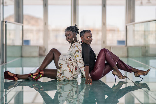 Relaxed black girl friends bonding and looking at camera