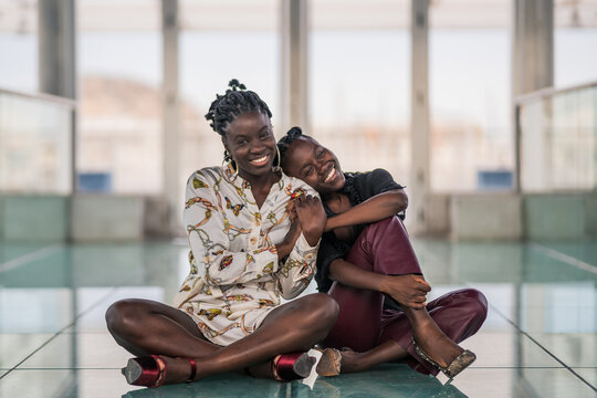 Relaxed black girl friends bonding and looking at camera