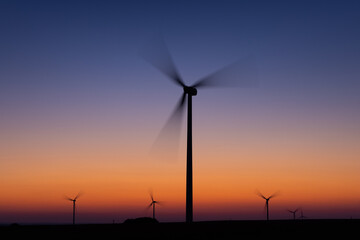 Fototapeta na wymiar Windmills producing renewable energy at sunset