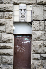 Unhappy statue face looking angrily at the vandalised door