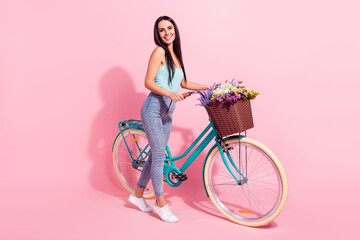 Full length body size photo woman riding retro bike in summer with flowers isolated pastel pink color background