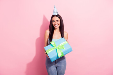 Fototapeta premium Photo portrait pretty brunette keeping big present box wearing festive cone isolated pastel pink color background