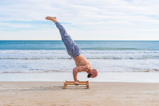 Man in handstand on parallel bars on coast