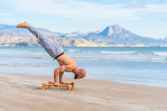 Man in handstand on parallel bars on coast