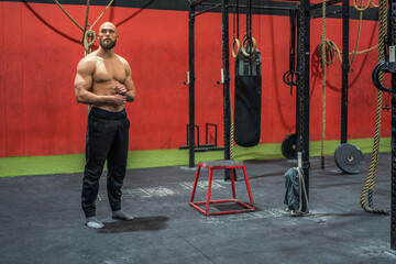 Strong sportsman looking away in gym