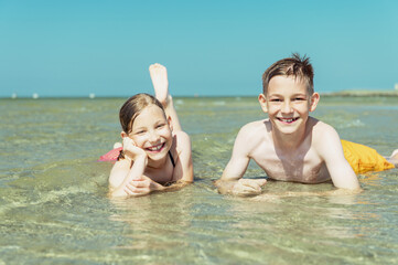 Portrait of two happy teen children liying in water of baltic sea beach at summer holidays