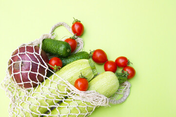 Ripe juicy red tomatoes, green cucumbers and zucchini in a string bag.