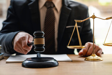 Man holds gavel judge with a lawyer, Judge with gavel at a wooden table indoors, closeup, the hammer in the hand of the judge. Criminal law