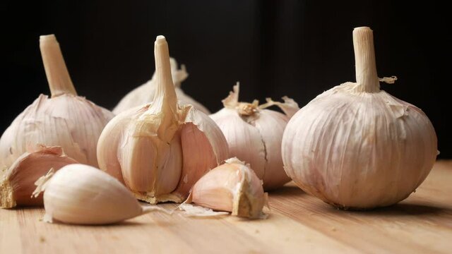 close up pf garlic on a chopping board against black background 