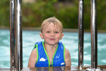 child in a swimming pool with a swimming vest