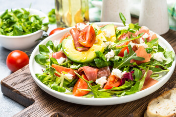 Green salad with avocado, salad leaves, jamon and tomatoes. Healthy diet lunch. Cloth up.