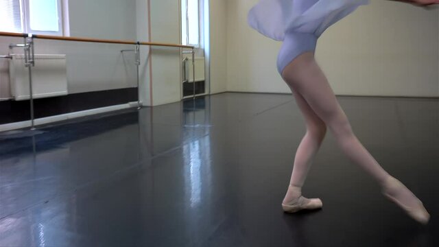 Young ballerina is performing  a diagonal rotation in a ballet class. 