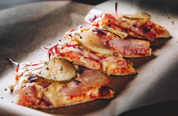 slice of Pizza with Mozzarella cheese, bacon, ham, tomato sauce, pepper, pickled cucumbers