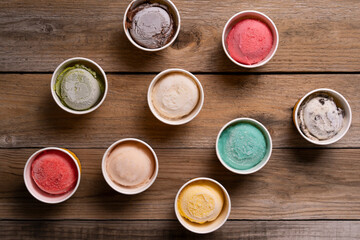 Top view or flat lay of Ice cream flavors in cup and topping on the wooden table, sweet and dessert...