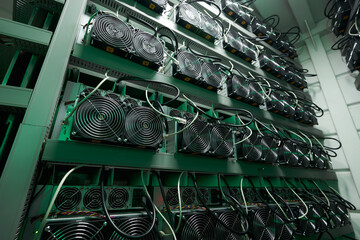 Bitcoin miners in large farm. ASIC mining equipment on stand racks mine cryptocurrency in steel container. Blockchain techology application specific integrated circuit datacenter. Server room lights.