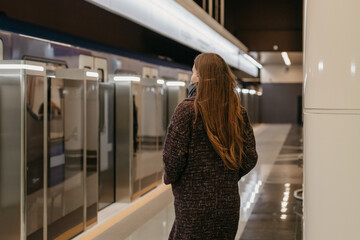 A woman in a medical face mask to avoid the spread of coronavirus is going to the modern subway...