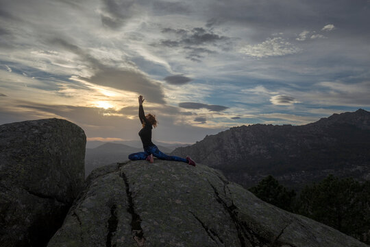 Woman performing Eka Pada Rajakapotasana on hilltop