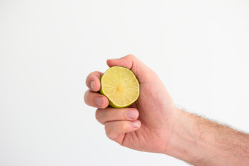 Fresh green halved lime held in hand by Caucasian male hand close up shot isolated on white