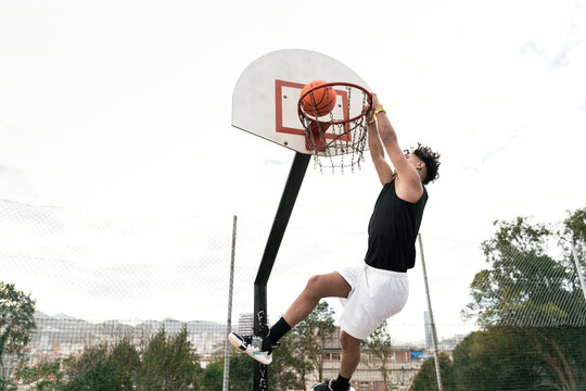 Ethnic man playing streetball on sports ground