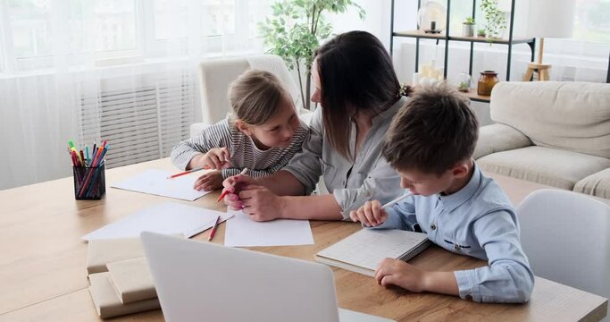 Mother helping daughter and son doing homework at home