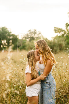 Mother kissing daughter in forehead in field